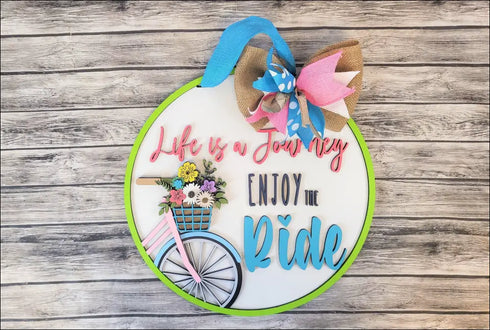 Circular handpainted wood door sign featuring a bicycle and floral basket for porch decor