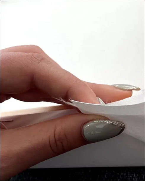 Hand peeling white wrapper on Our Song canvas with scannable Spotify code