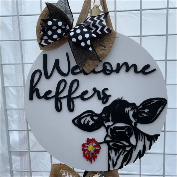 Round Welcome Heifers Door Hanger sign featuring a cow and bow, ideal farmhouse decor
